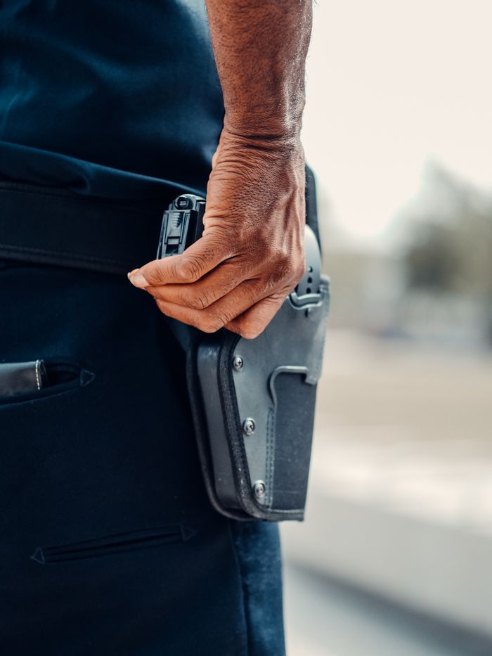 testimonial-img A police officer's hand gripping the holster of a handgun, symbolizing readiness and security.